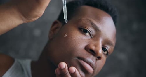 Young Adult Applying Facial Serum from Dropper