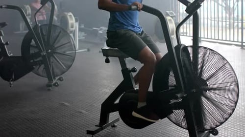 Focused biracial man training on elliptical bike at gym, slow motion