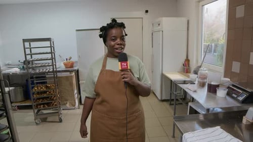 Woman in Commercial Kitchen Talking Into Microphone