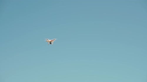 White Remote Controlled Drone Equipped with High Resolution Video Camera Hovering in Mid Air with