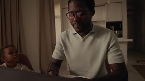 Father Works at Table with Child Nearby