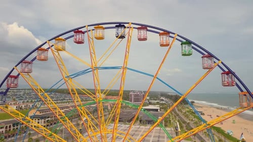 Aerial View of Around a Nonspinning Ferris Wheel in an Amusement Park with the Sea and Beach in the