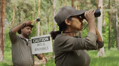 Female Forest Ranger Looking out for Wild Animals through Binoculars