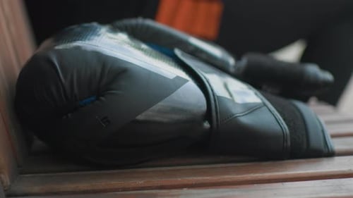 Person Prepares Boxing Gloves and Wraps on Bench