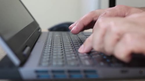 13Close-up of hands using a laptop keyboard and mouse on a wooden desk. Work, internet browsing, and