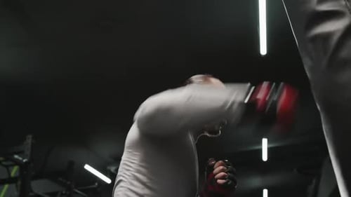 Angry Boxer Punching Bag in Gym From Below Energetic Male Fighter Punching Heavy Bag Aggressively