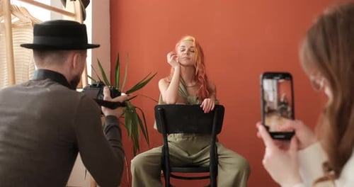 Fashion Model on Photo Session in the Studio Assistant Shoots Backstage on Smartphone While
