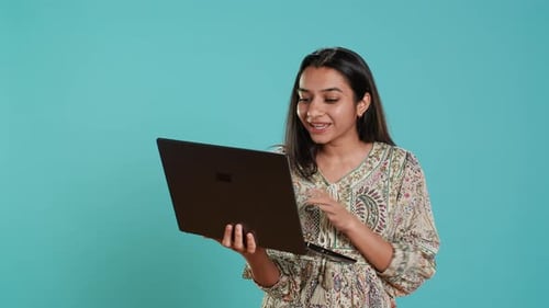Woman Interacts with Laptop on Blue Background