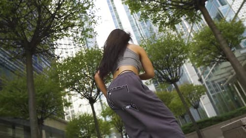Urban hip hop street dancer with joggers sports bra and trainers is moving her body like a pro vario