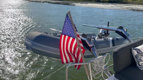 Vista de perto, traseira do veleiro com bandeira suja e americana navegando em dia ensolarado