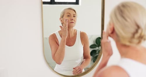 Senior Woman Applying Moisturizer in Bright Modern Bathroom