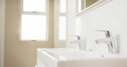 Close up of basin and chrome taps in bathroom, slow motion