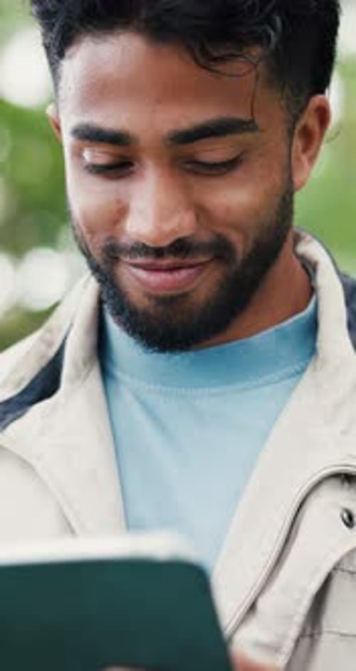 Smiling Man Looking at Tablet Outdoors