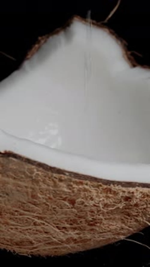Pouring Coconut Water Into a Freshly Halved Coconut