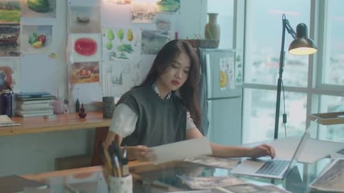 Asian Woman Working with Drawings and Laptop in Art Studio