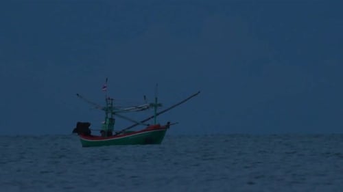 Fishing Boats in Thailand wait in the middle of the ocean for dark to come so they can turn on their