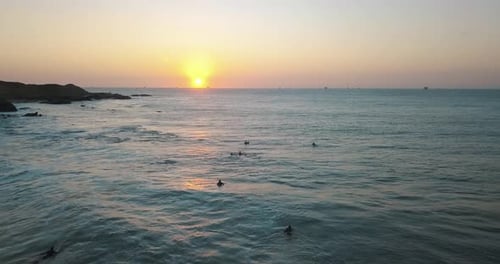 Drone aerial view a beautiful Sunset on the pacific ocean and surfers waiting for the waves by the c