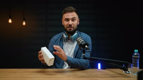 Enthusiastic man unboxing a new smartphone at desk