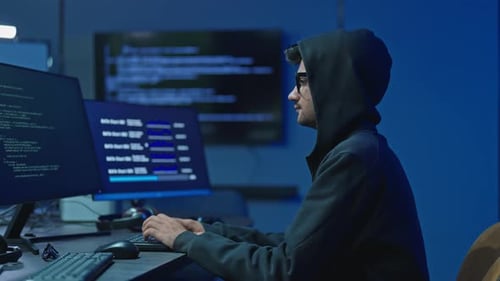 Un hacker anonyme en sweat à capuche codant sur des écrans d'ordinateur