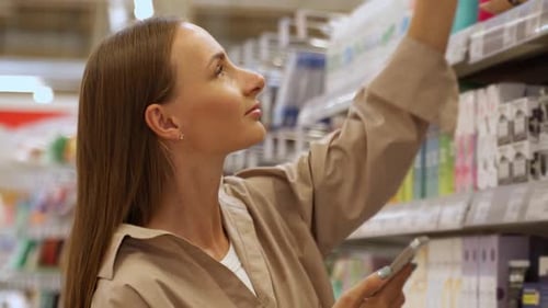 A Woman in a Beige Shirt Browse Through the Shelves in a Grocery Store She is Looking at a Variety