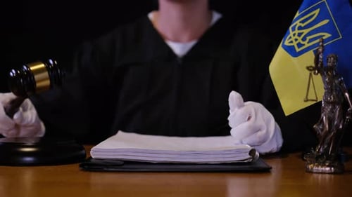 Judge Striking Gavel in Ukrainian Courtroom with National Flag and Scales of Justice