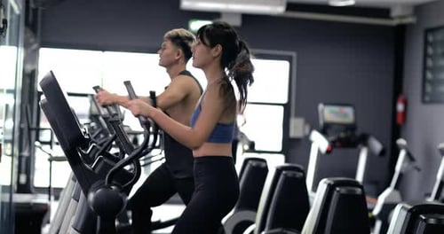 Young asian woman cardio exercising with elliptical gym equipment.
