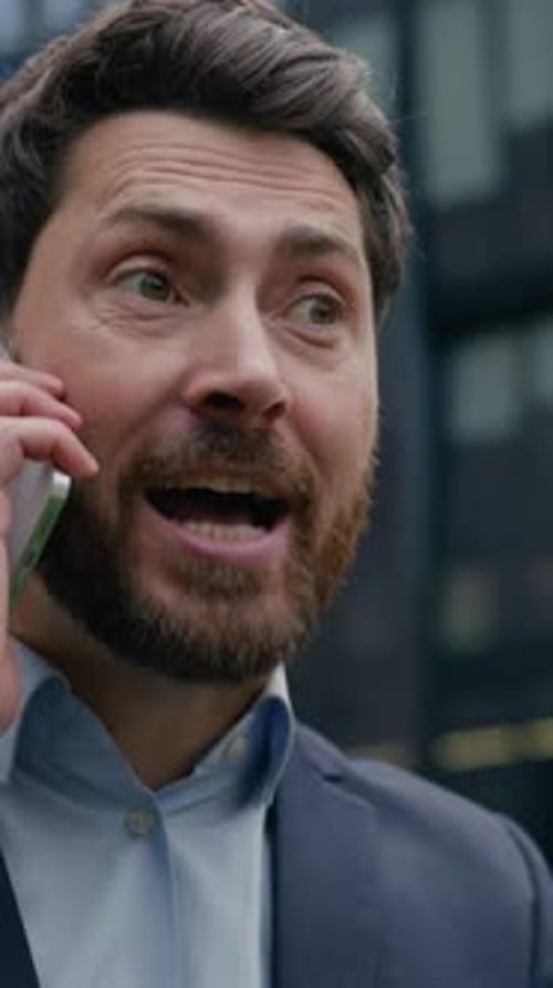 Frustrated Man Talking on Phone Outside Building