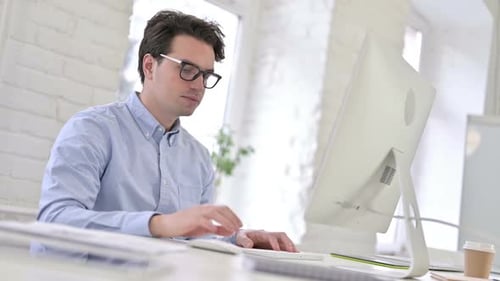 Focused Working Young Man using Laptop in Modern Office