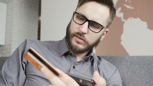 One Businessman Sit in Office Hold Visa Bankcard and Typing at Telephone