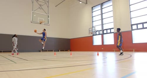 Playing basketball, athletes practicing shooting and passing drills in indoor gym