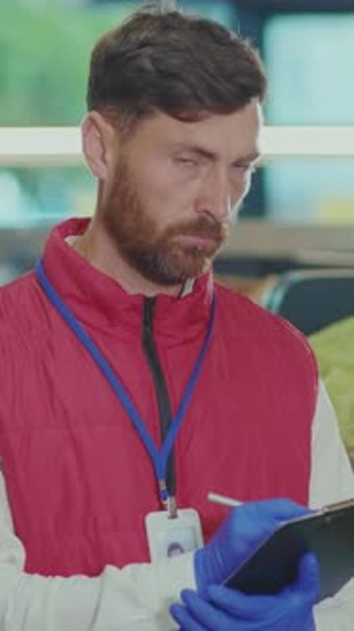 Man Wearing Protective Gloves Writing on Clipboard Indoors