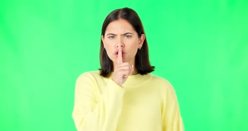 Secret, green screen and face of serious woman in studio, finger and lips on background for privacy
