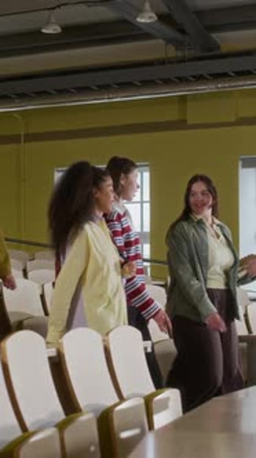 Intercultural Gen Z Peers Walking along Desks in University Classroom