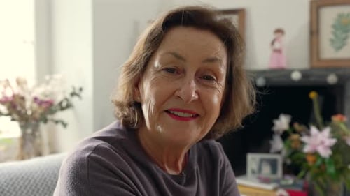 Senior Woman Smiles While Sitting on Couch Indoors