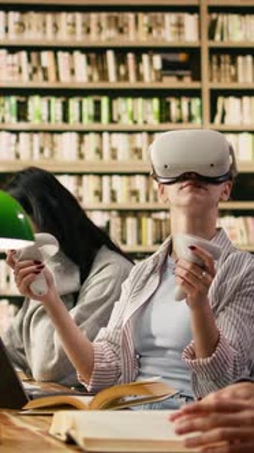 Vertical Video Student Wears VR Glasses and Holds Controllers in University Library