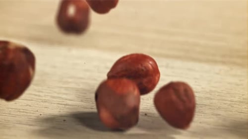 Hazelnuts Falling on a Wooden Table Surface