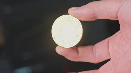 Hand Holds Gold Bitcoin in Close Up
