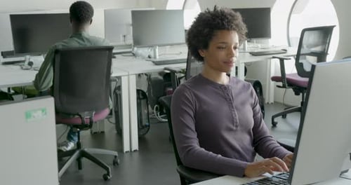 Black Young Adult Female Engineer in Office Coding on Computer