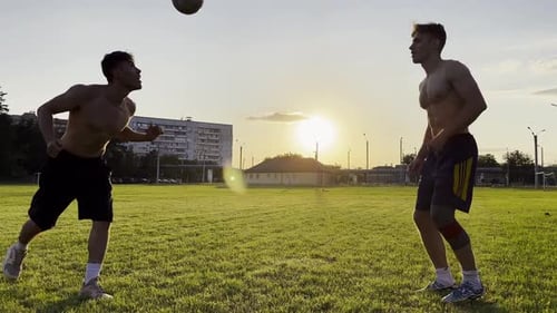 Two Sportsmen Showing Tricks with Ball While Passing It to Each Other at Field Young Men Kicking
