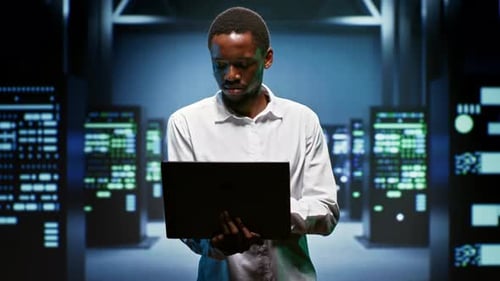 Afroamerikanischer Ingenieur verwendet Laptop zur Inspektion von Rackmount-Servern