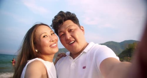 A Young Happy Asian Couple Enjoys Their Vacation Taking Joyful Selfies and Smiling They Pose