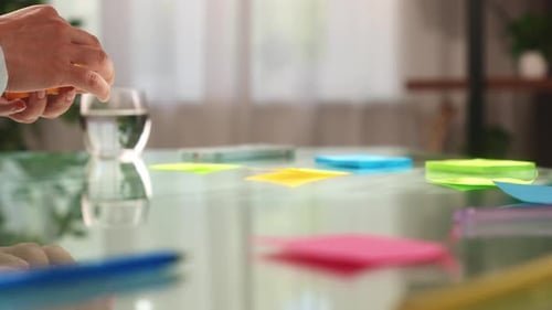 Hands Organizing Colorful Sticky Notes on Table Surface