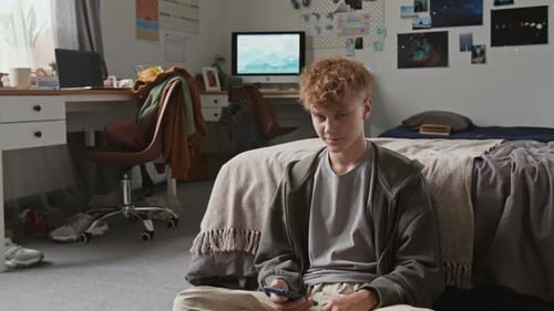 Teenage boy smiles while using his cellphone at home