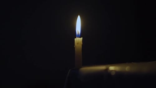 Single Candle Flame Flickers in Dark Setting