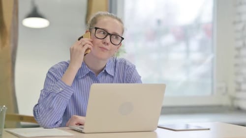 Woman Angrily Talking on Cell Phone at Desk