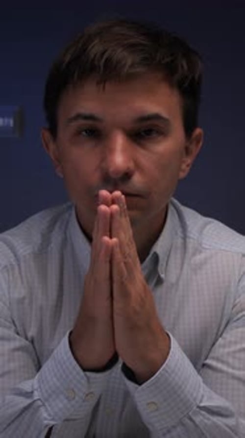 Man with hands together in indoor setting