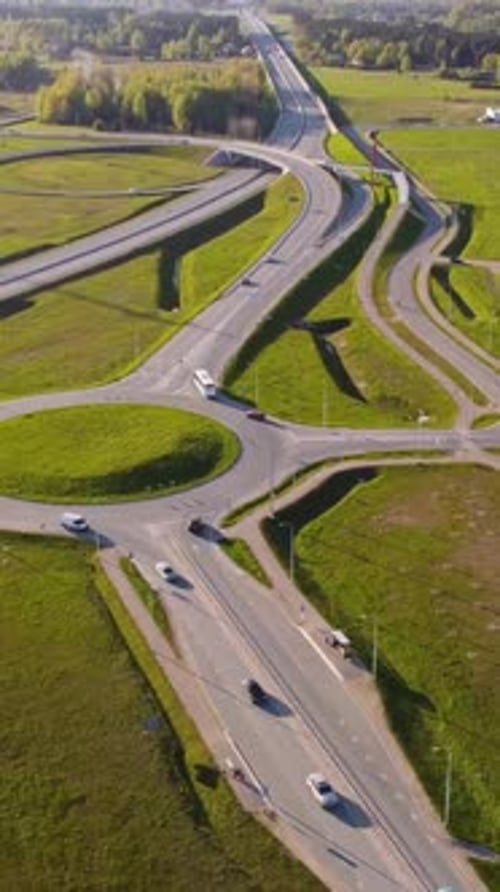 Katlakalns spring road interchange showing traffic, curved highway ramps, green fields, vertical