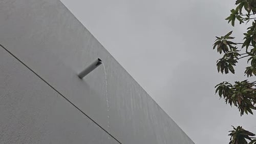 Water flows from building pipe after a rain