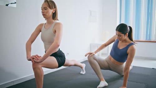 Women Exercising, Stretching in Bright Room
