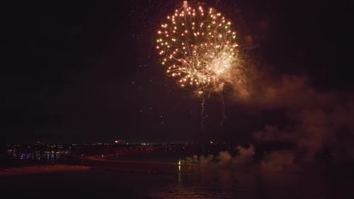 Vista aérea de fogos de artifício brilhantes explodindo com luzes coloridas sobre a costa do mar no Dia da Independência dos EUA
